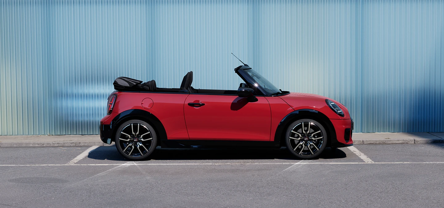 Side view of the MINI Cooper Convertible in Chili Red on a street.