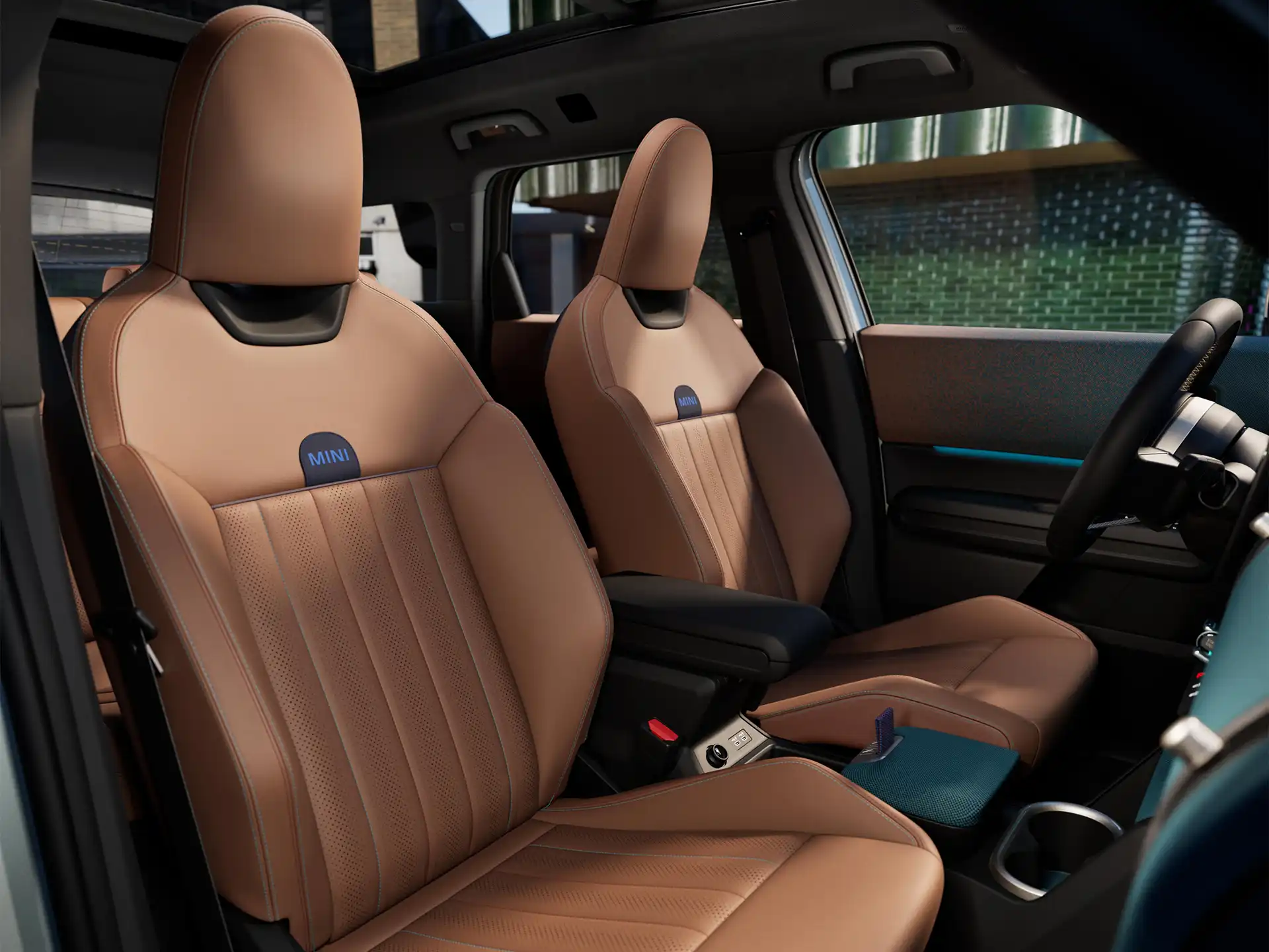 Interior perspective of the all-electric MINI Countryman is showing the dashboard, steering wheel, round display, panorama glassroof and back of the frontseats.