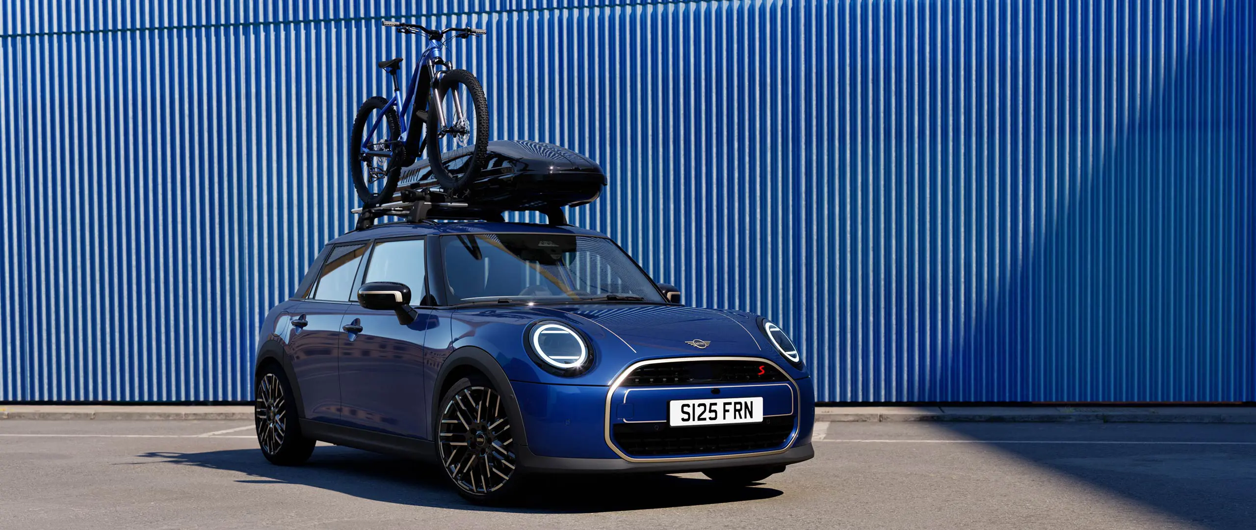 マウンテンバイクとミニルーフボックス320を搭載したミニルーフバイクラック付きのインディゴサンセットブルーのMINIエースマンの正面図。