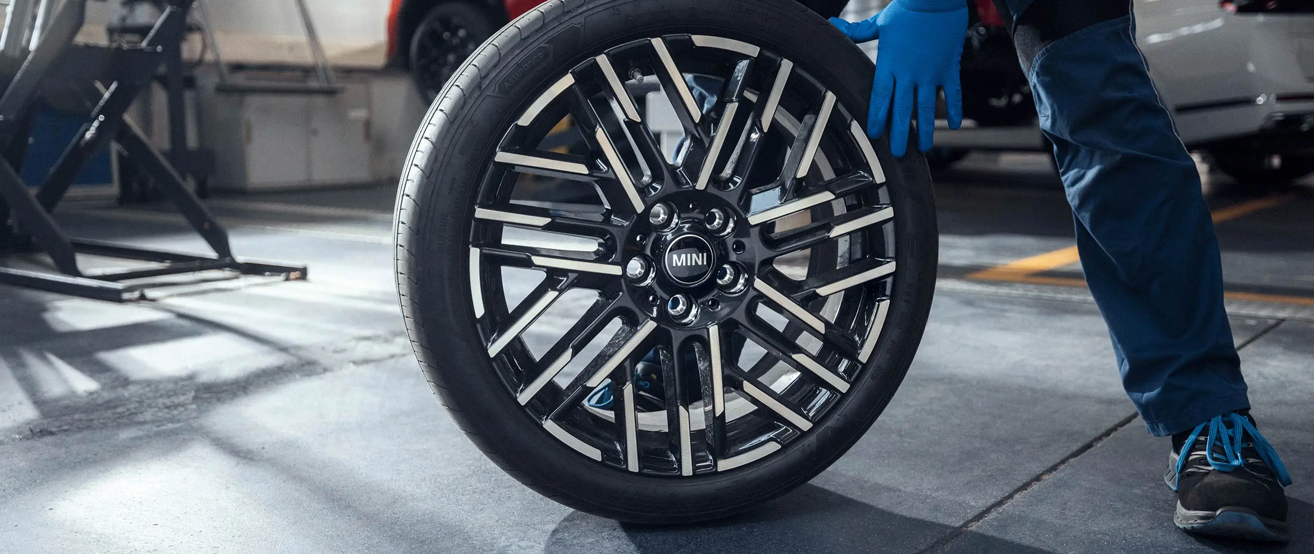 MINIパートナーのサービス技術者が、18インチのナイトフラッシュスポークバイカラー軽合金ホイールを所定の位置に転がします。