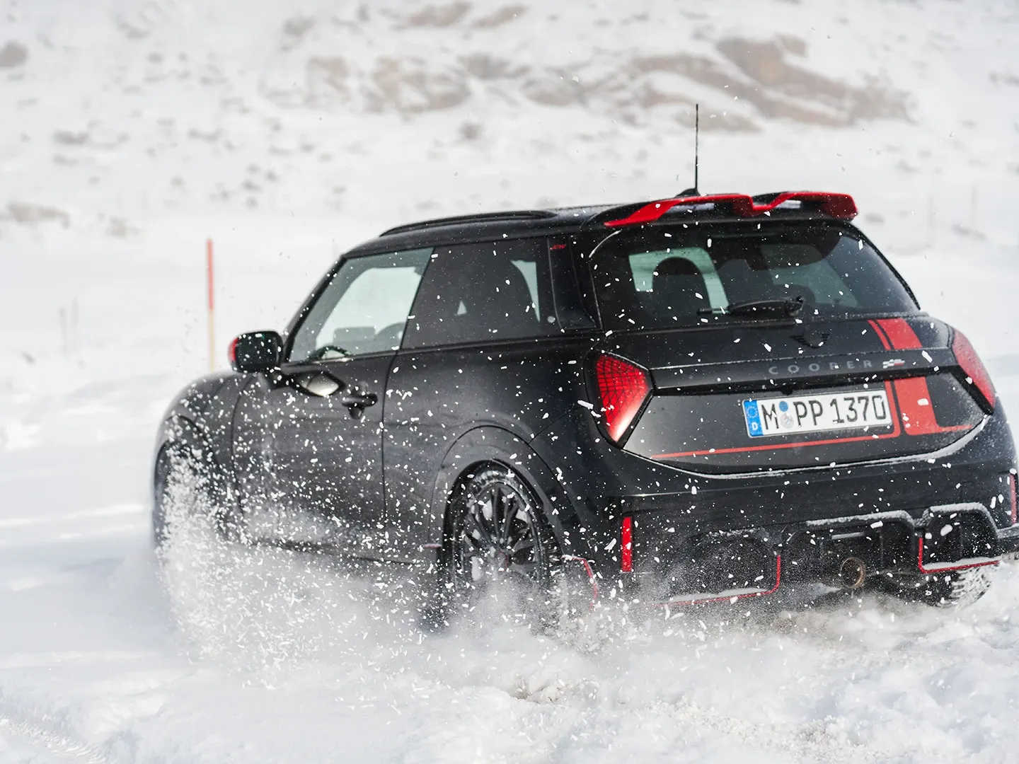 雪の中を走行するMINI Cooper JCWの後ろ姿。