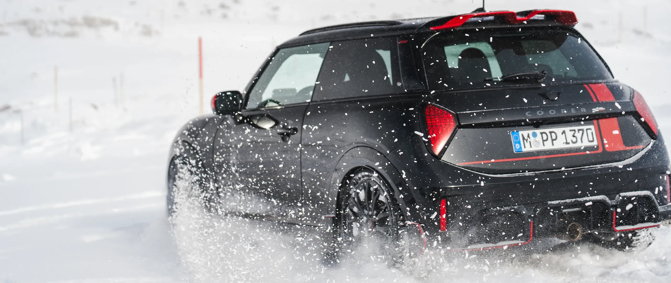 雪の中を走行するMINI Cooper JCWの後ろ姿。