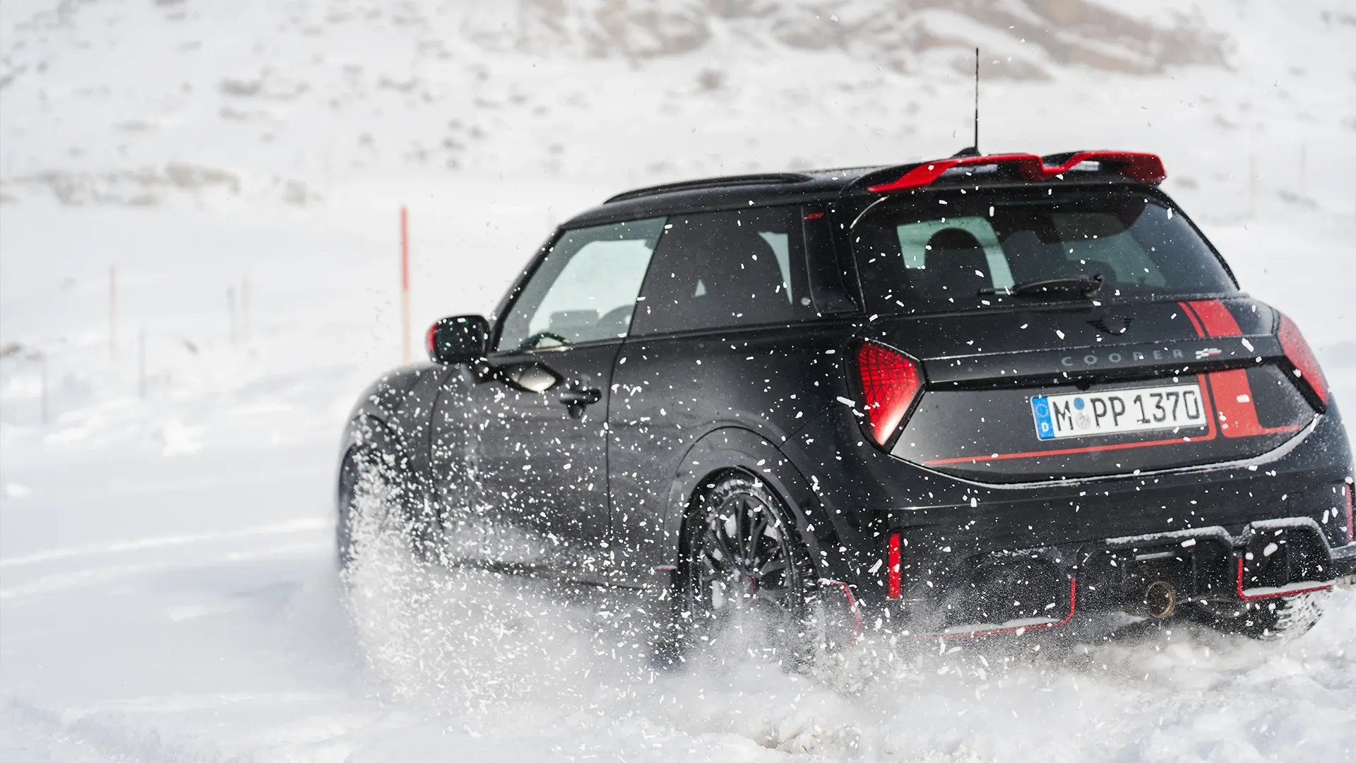雪の中を走行するMINI Cooper JCWの後ろ姿。