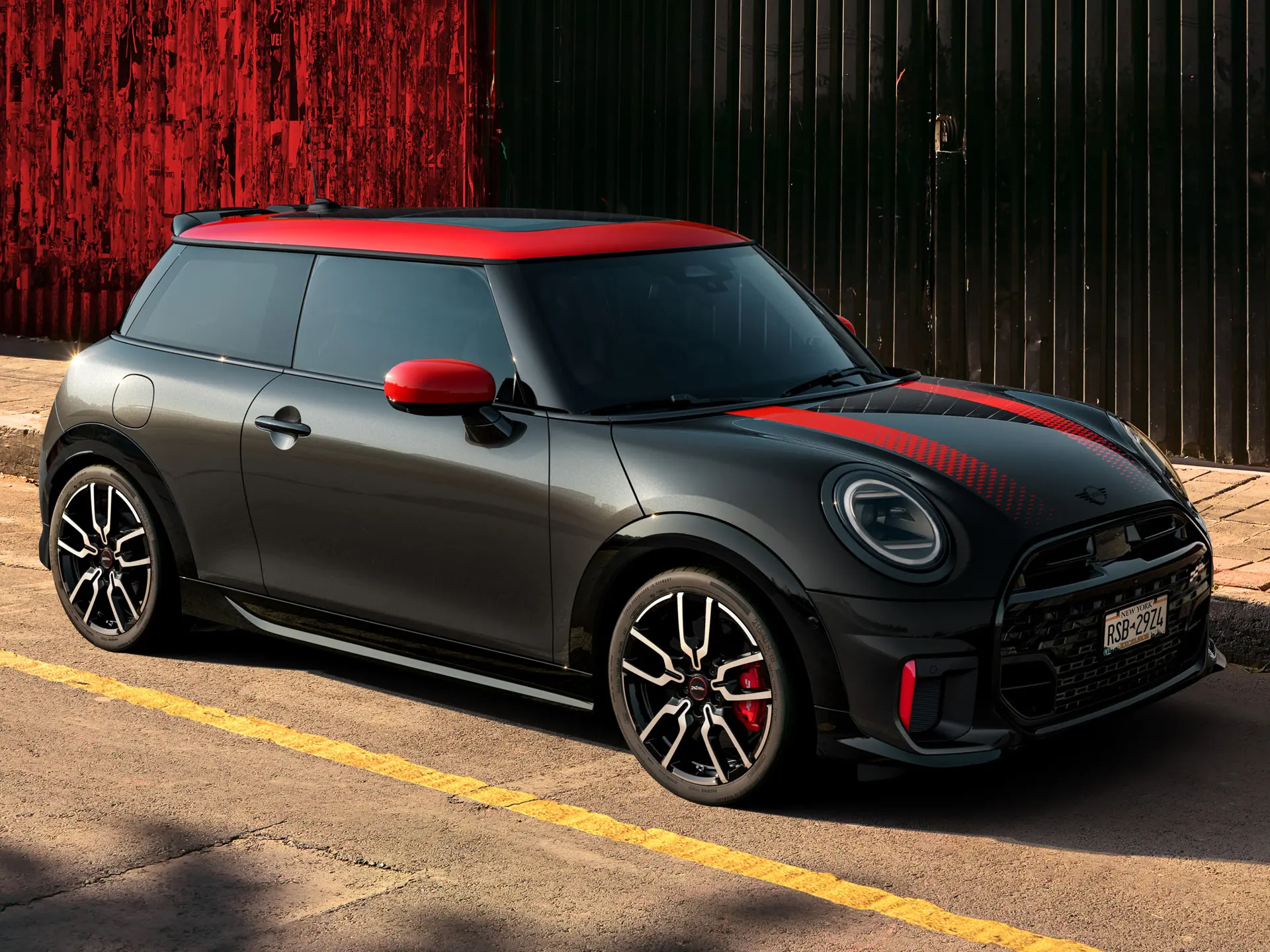 MINI John Cooper Works 3ドアミッドナイトブラック、ルーフキャップとミラーキャップはチリレッド、スポーツストライプレッドはレッドで、サイドビュー、路上駐車時。