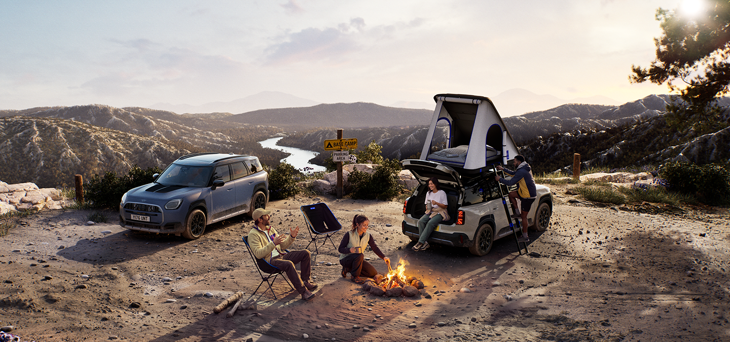 Image of two MINI Countryman Untamed Edition vehicles on a mountain in a sunset.