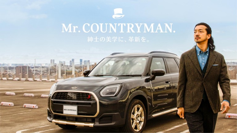 MINI Countrymanを背景にして俳優の金子ノブアキさんを駐車場で撮影した画像 